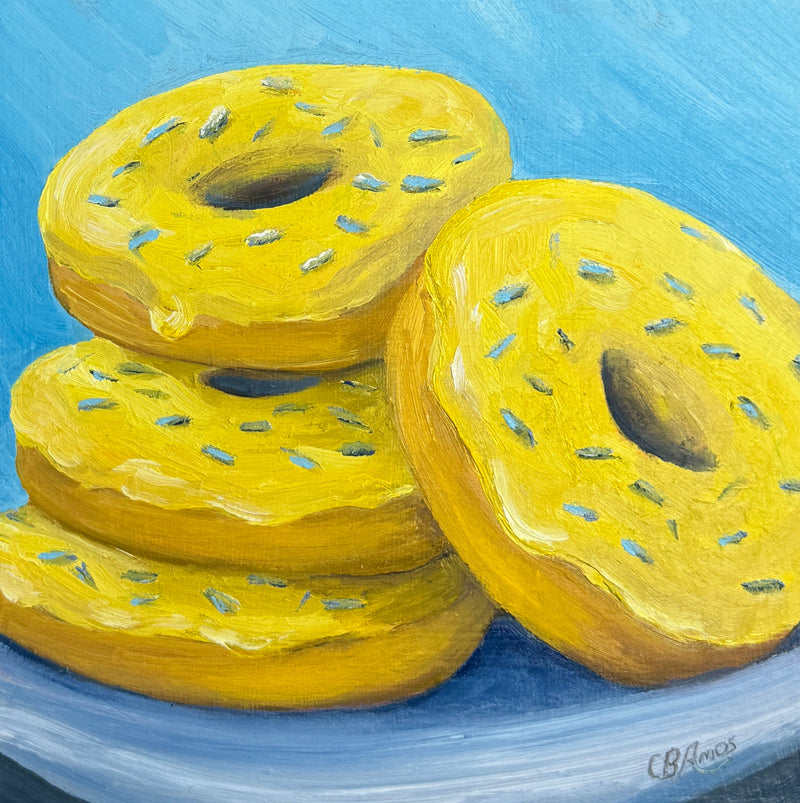 Painting of yellow donuts with blue sprinkles on a blue background